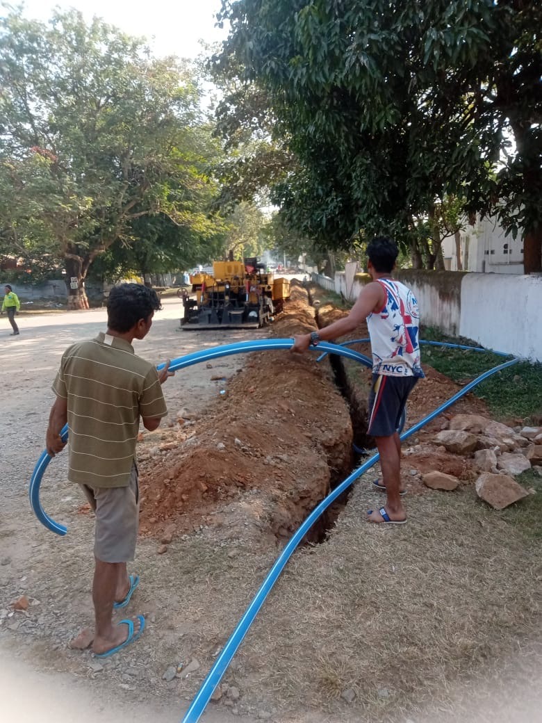 Crew laying HDPE duct into a roadside trench